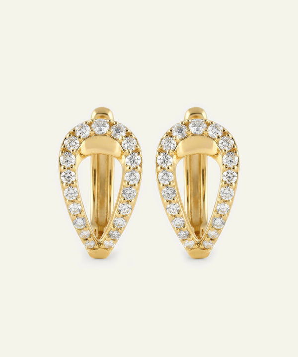 Gold hoop earrings with diamond accents on a light beige background