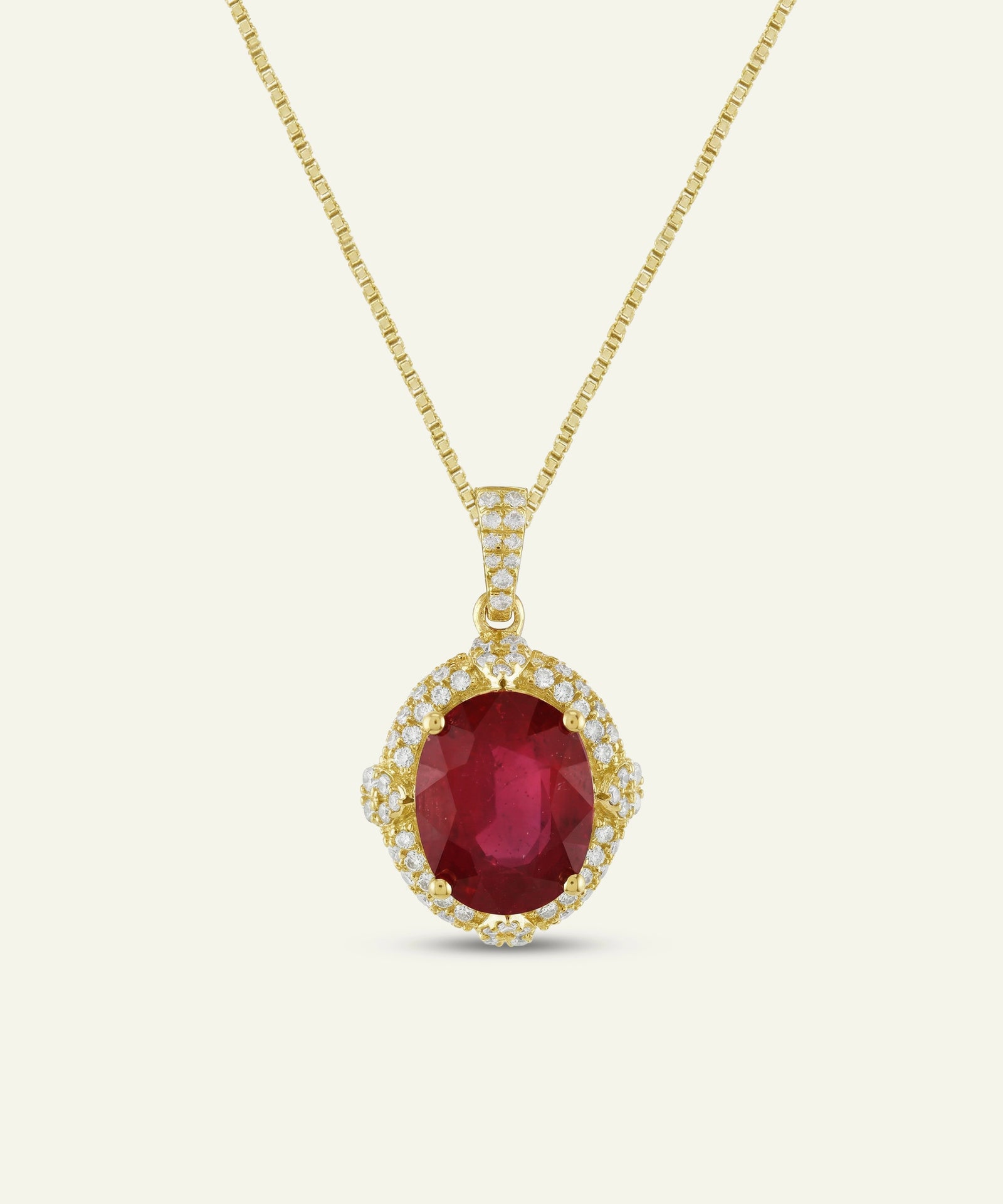 Oval ruby halo pendant necklace on a yellow gold chain.
