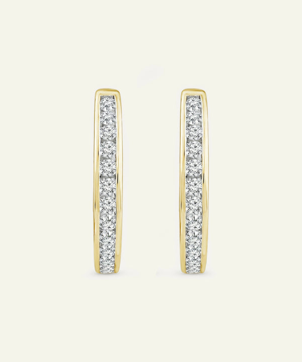 Gold hoop earrings with embedded diamonds on a light beige background