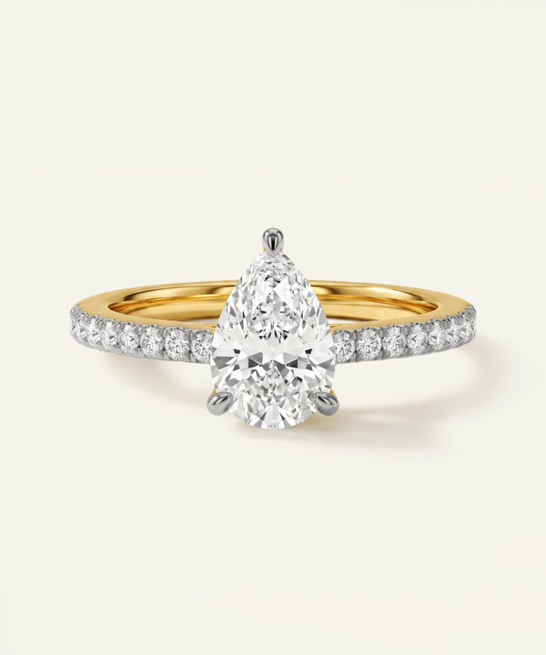 Gold and diamond ring with a pear-shaped diamond on a white background