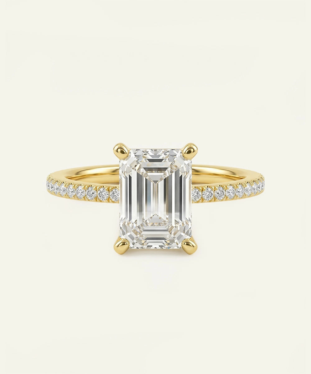 Gold ring with a large emerald-cut diamond and smaller diamonds on a white background