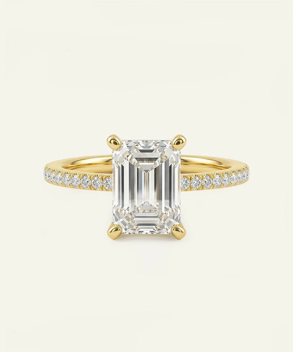 Gold ring with a large emerald-cut diamond and smaller diamonds on a white background