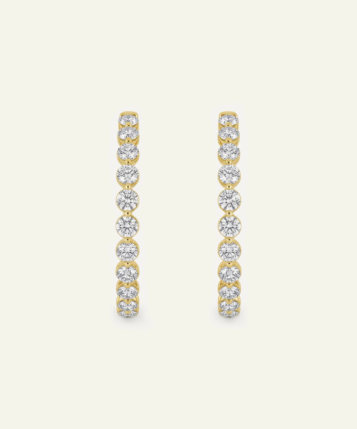 Gold and diamond earrings on a light beige background