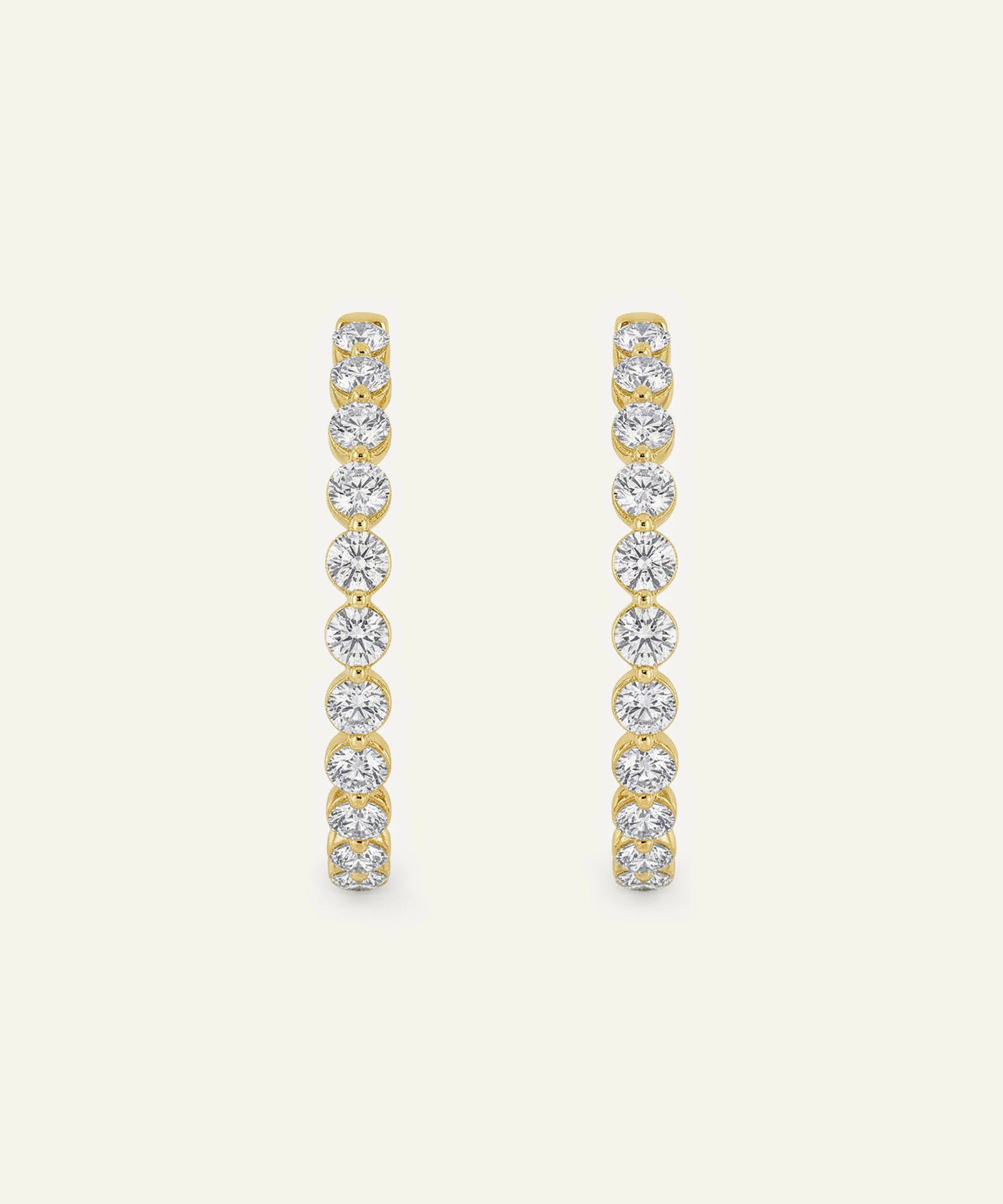 Gold and diamond earrings on a light beige background