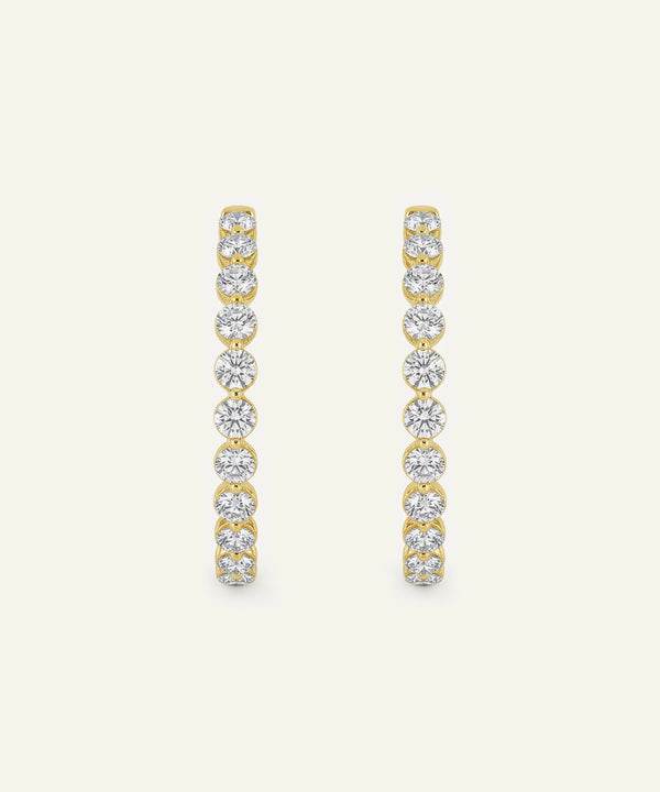 Gold and diamond earrings on a light beige background