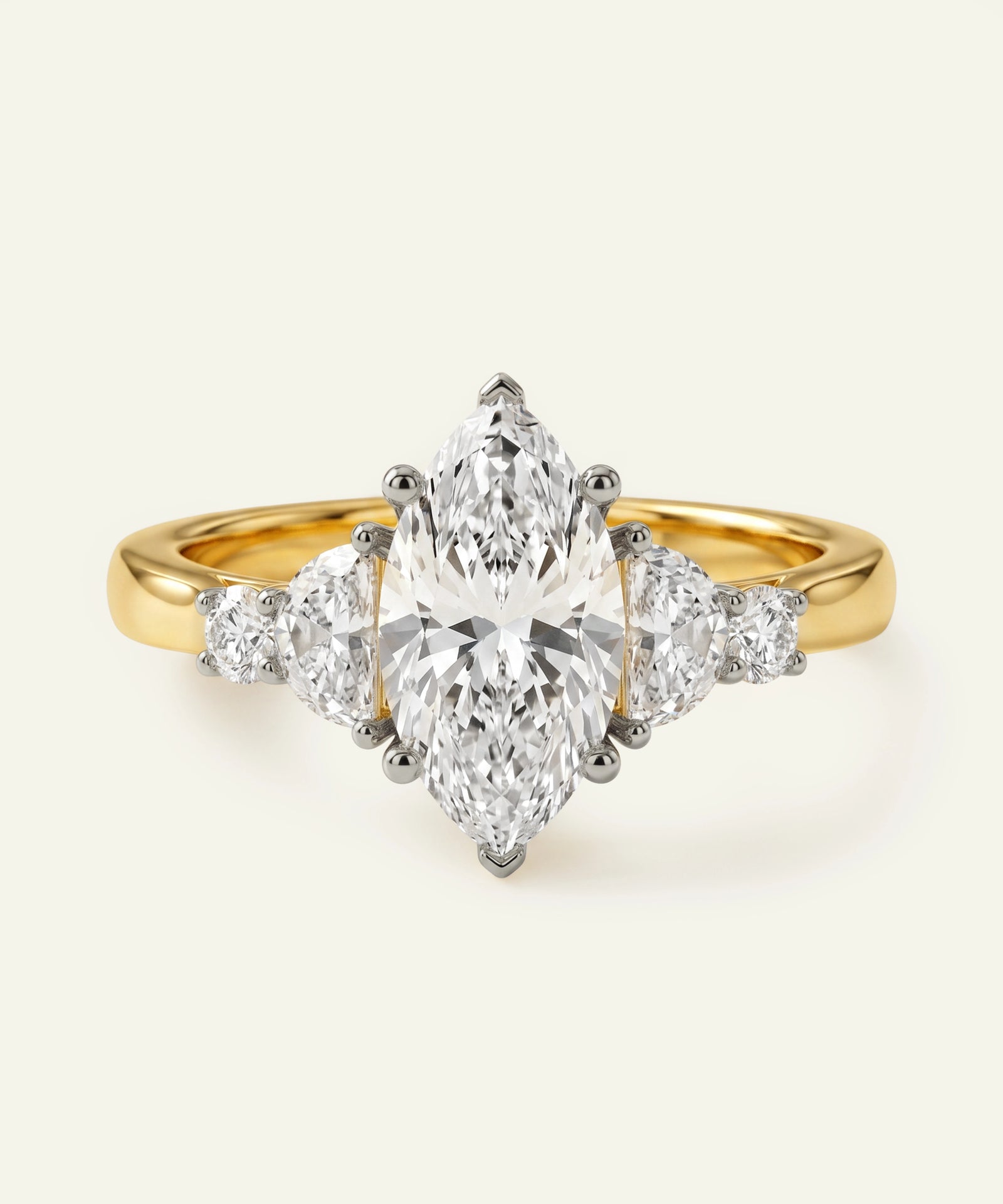 Gold ring with a central pear-shaped diamond and smaller side diamonds on a white background