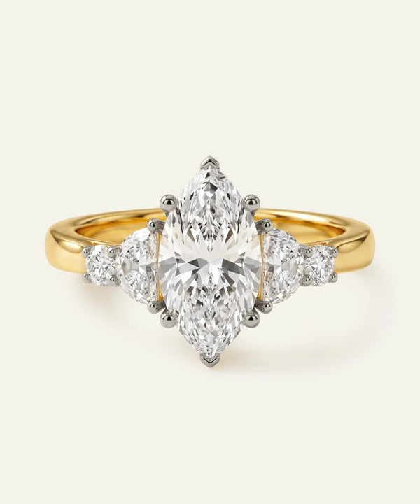 Gold ring with a central pear-shaped diamond and smaller side diamonds on a white background