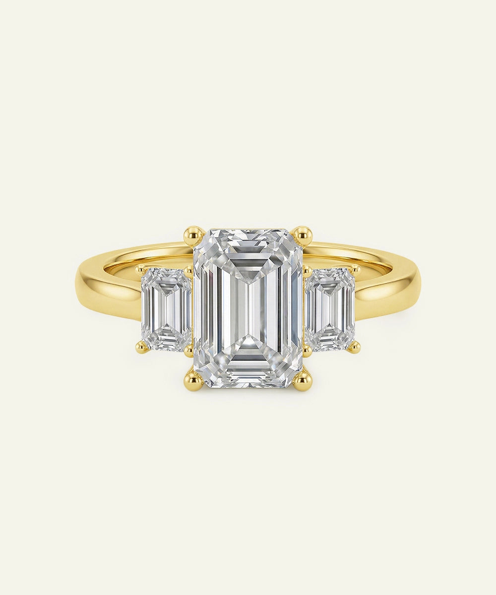 Gold ring with emerald-cut diamonds on a white background