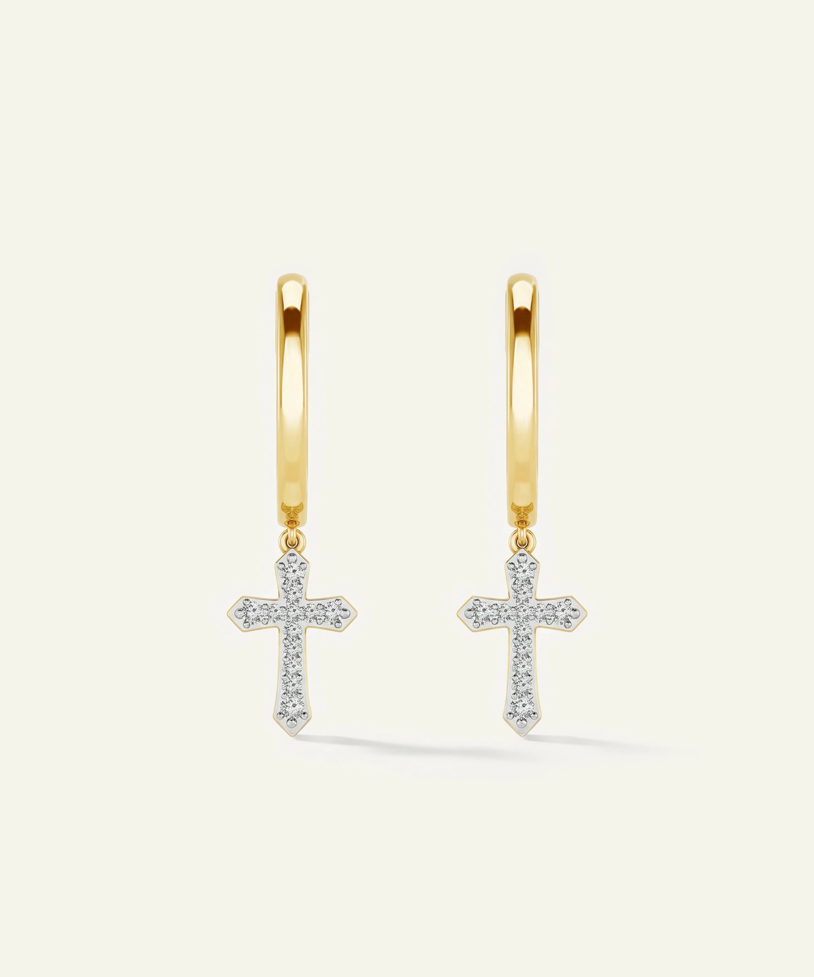 Gold hoop earrings with cross pendants on a light beige background