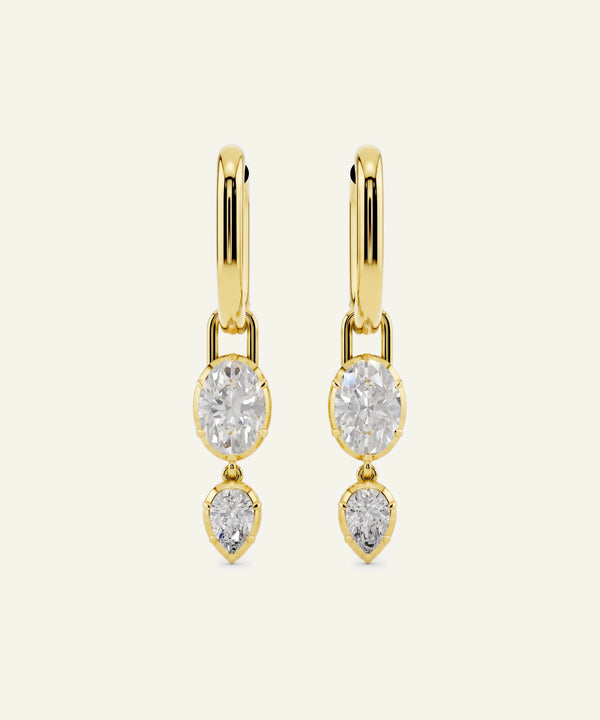 Gold earrings with three clear gemstones on a white background