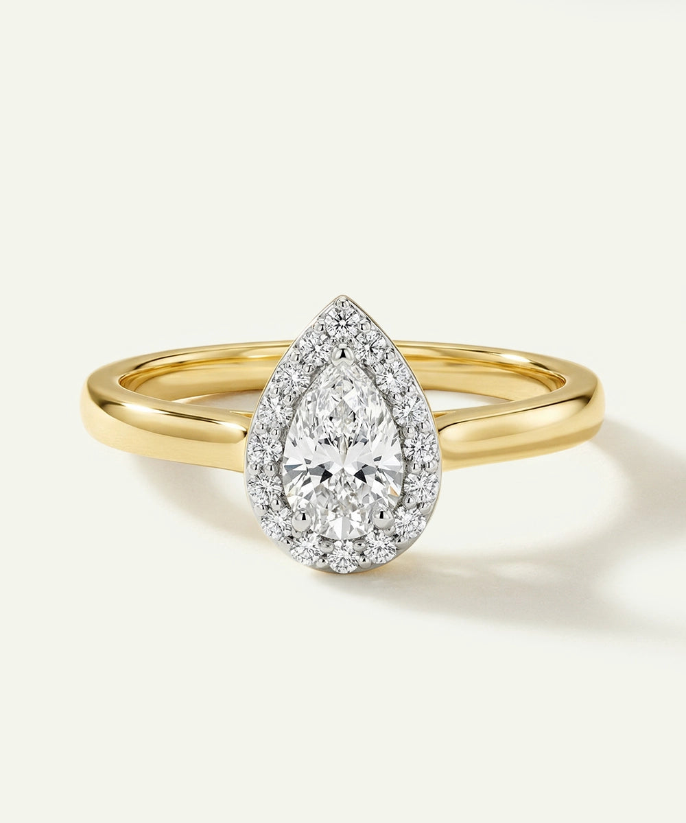Gold ring with a pear-shaped diamond on a white background