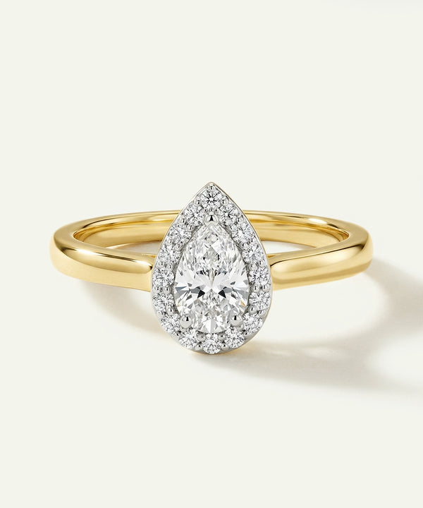 Gold ring with a pear-shaped diamond on a white background