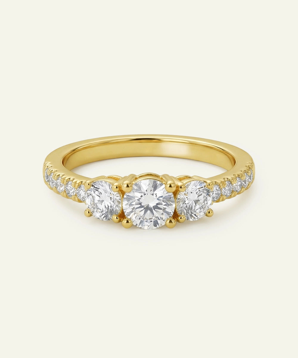 Gold ring with three diamonds on a light beige background