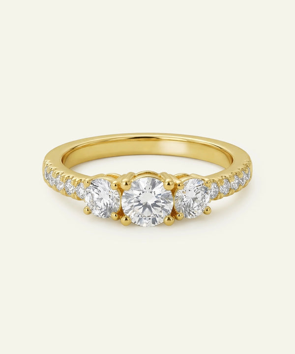 Gold ring with three diamonds on a light beige background
