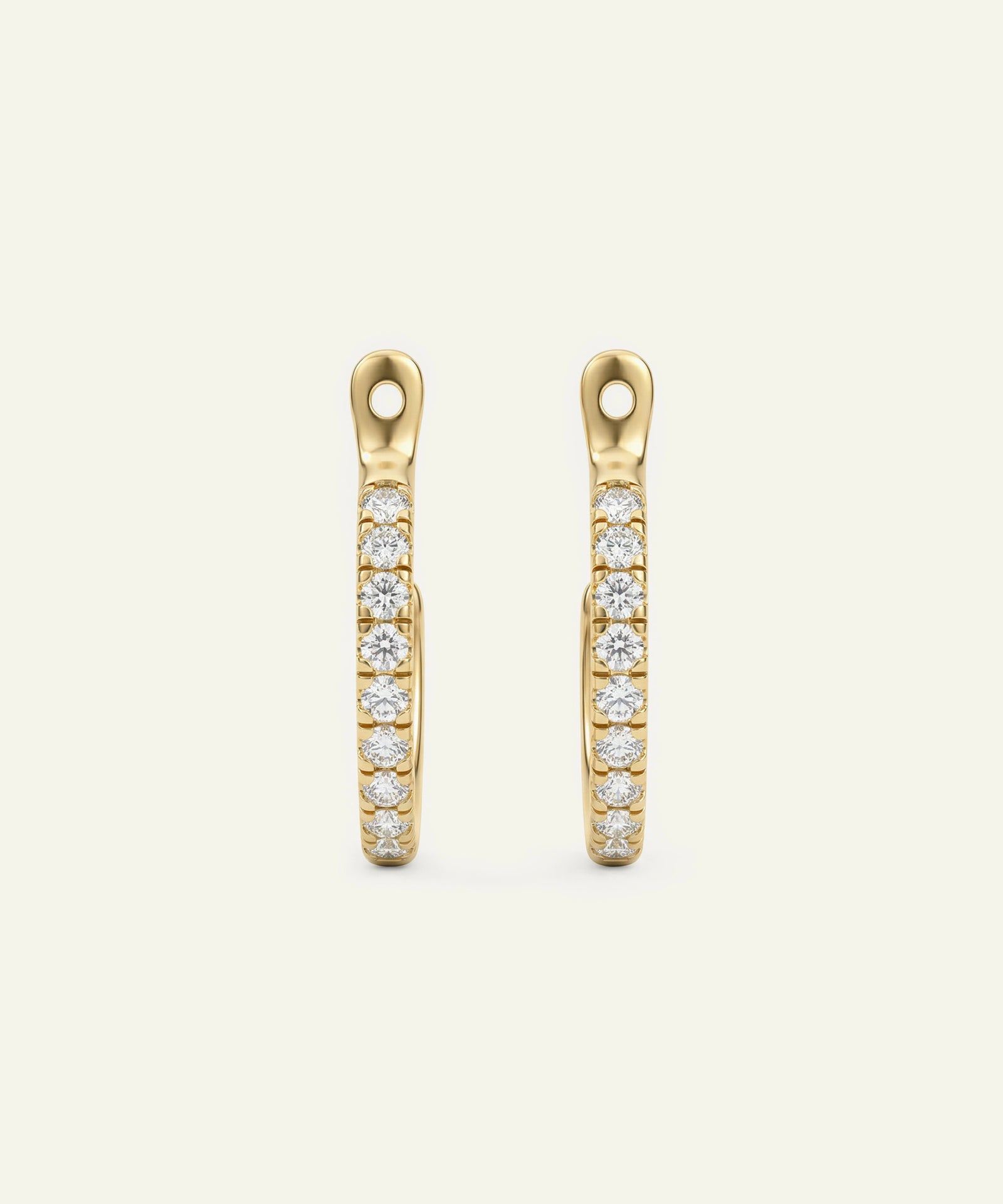 Gold earrings with embedded diamonds on a beige background