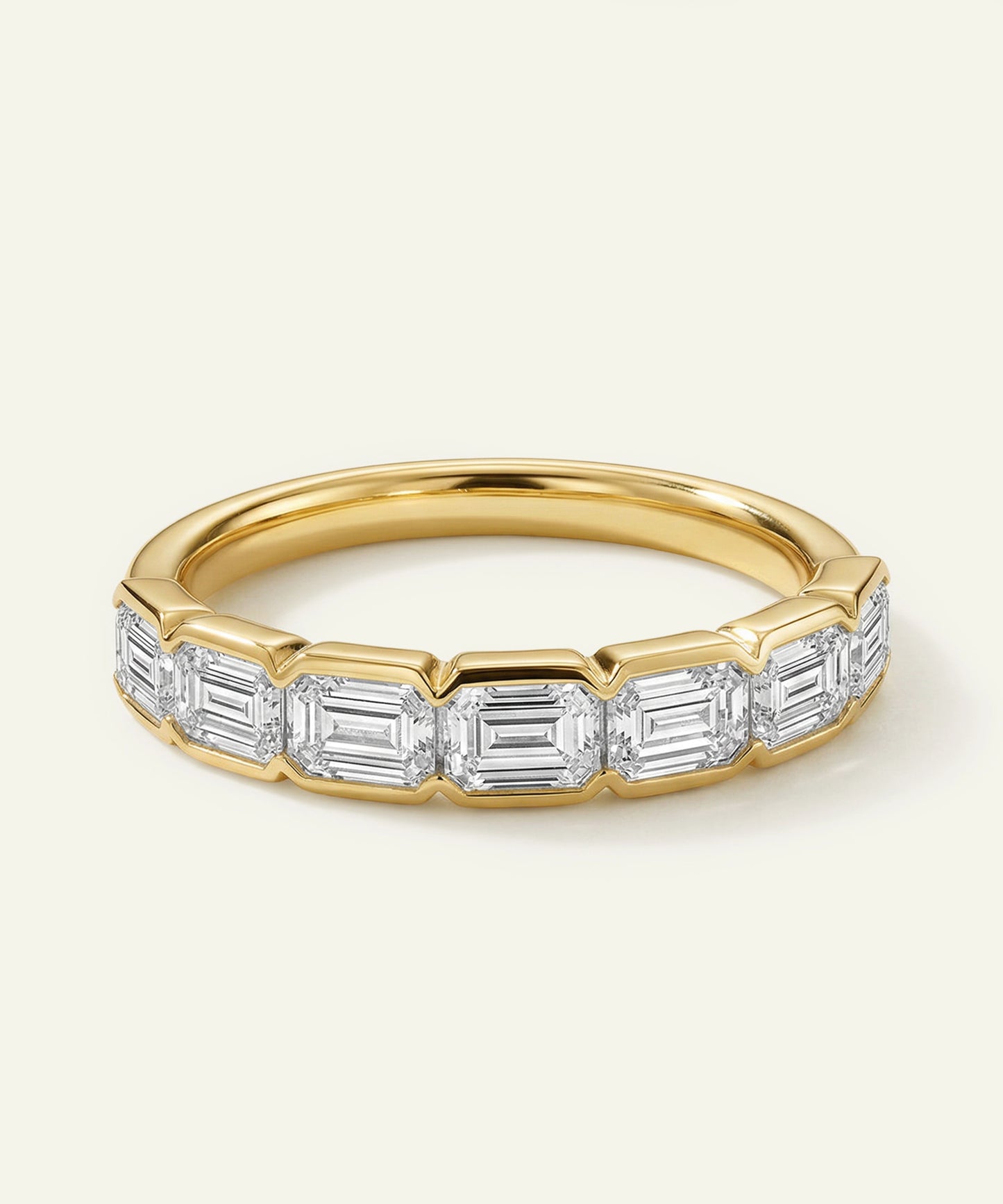 Gold ring with emerald-cut diamonds on a light background