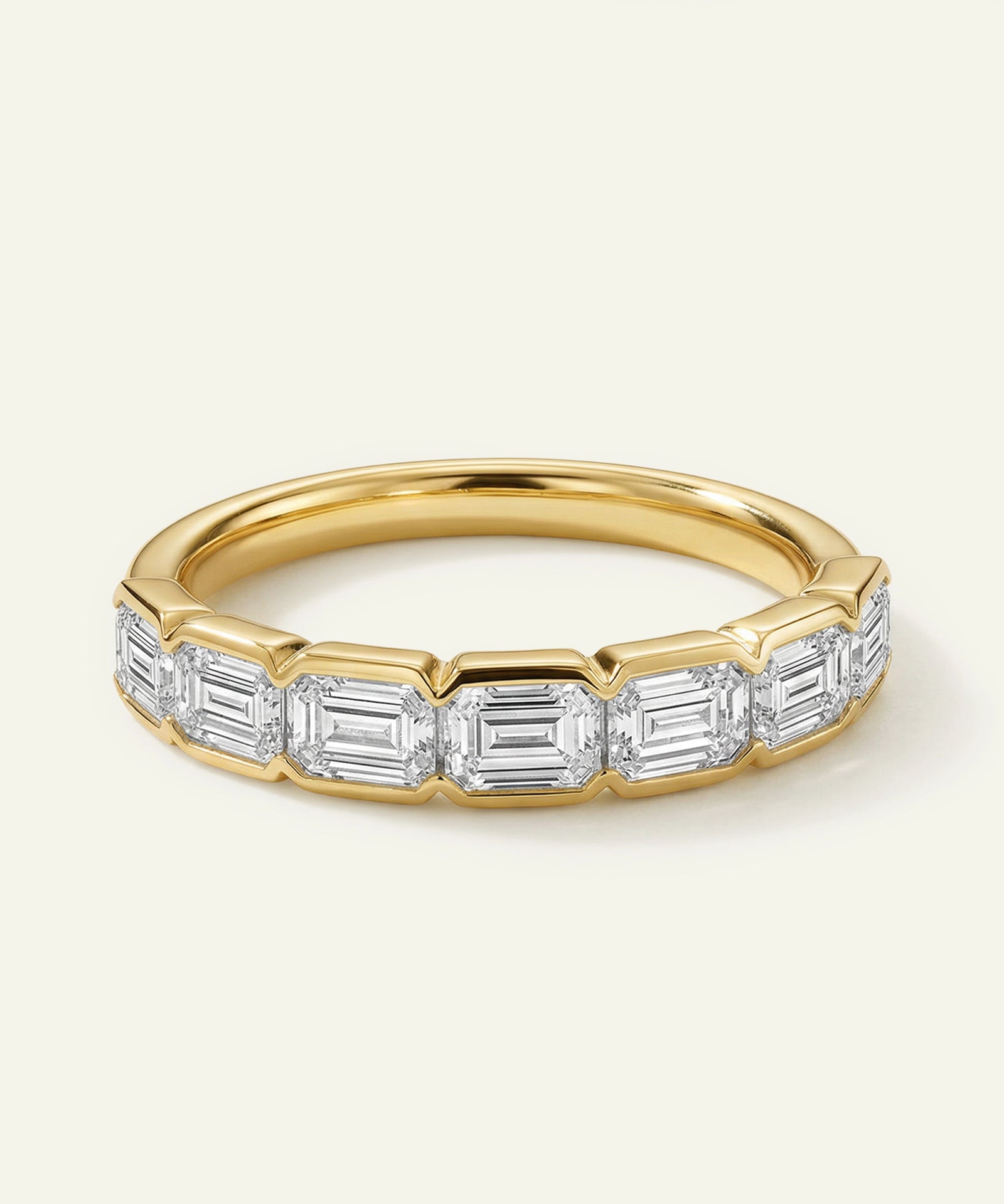 Gold ring with emerald-cut diamonds on a light background