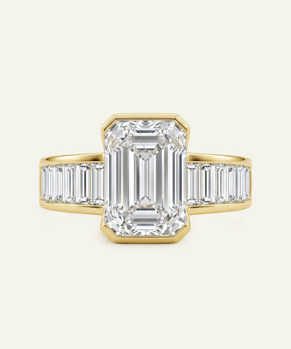 Diamond ring with emerald-cut center stone and baguette side stones on a white background