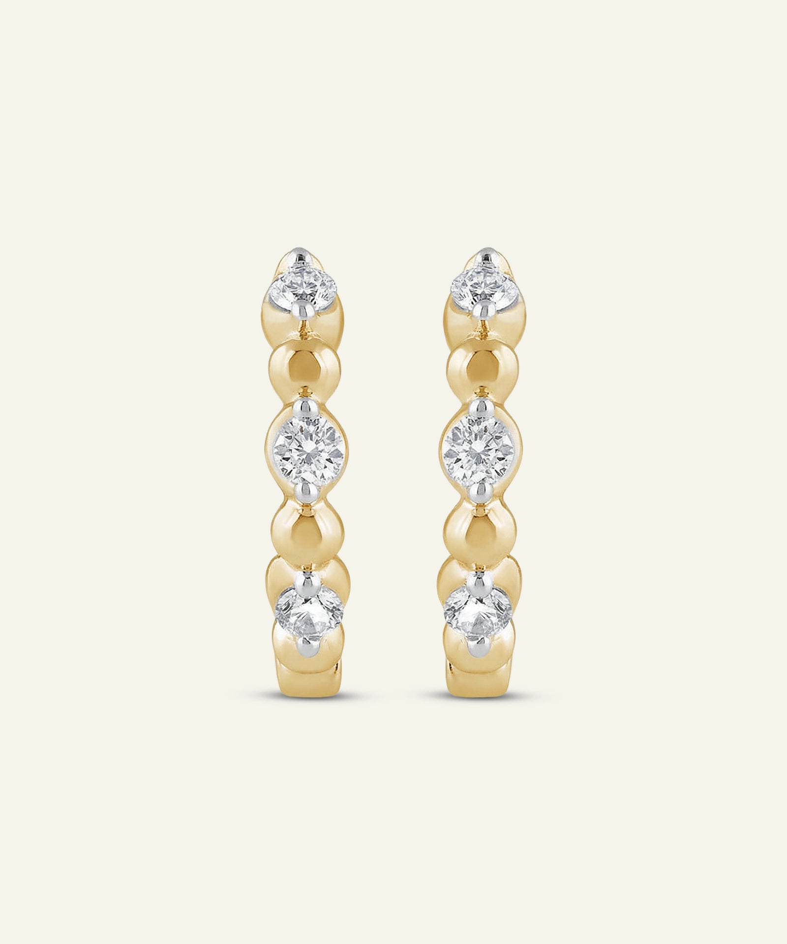 Gold earrings with clear gemstones on a white background