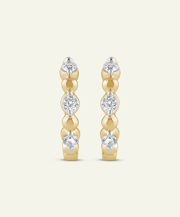 Gold earrings with clear gemstones on a white background