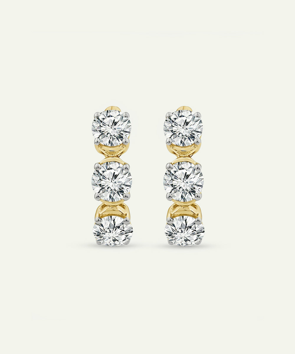 Pair of gold and diamond earrings on a light gray background