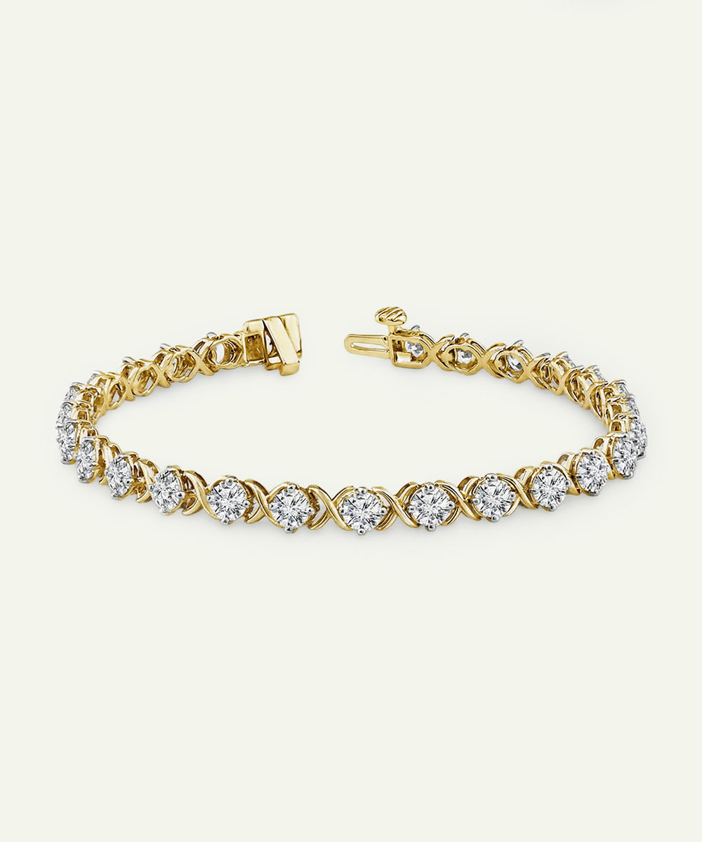Yellow gold diamond tennis bracelet featuring an alternating pattern of prong-set round brilliant cut diamonds and polished gold X-shaped links, with a secure box clasp.