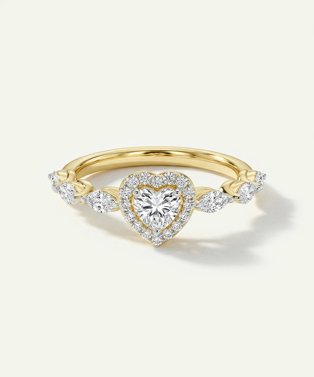 Gold ring with a heart-shaped diamond on a light beige background