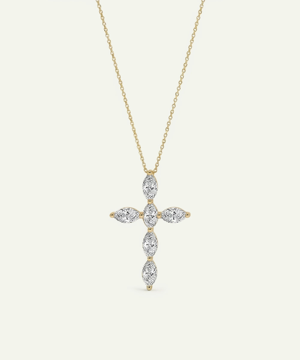 Gold cross-shaped pendant necklace with diamonds on a light beige background