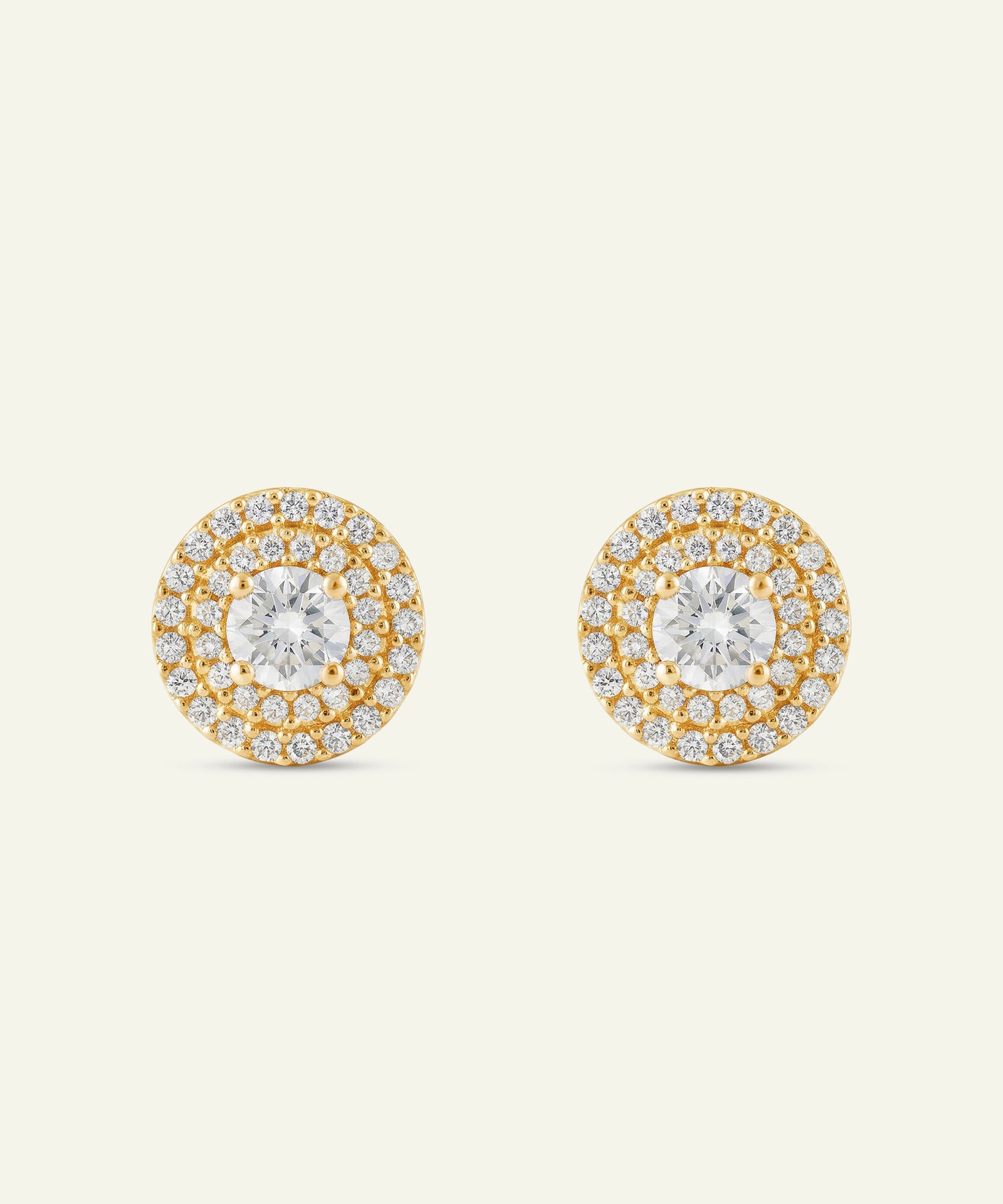 Pair of gold and diamond earrings on a light beige background