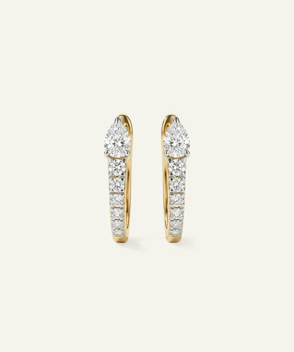 Gold hoop earrings with diamond accents on a light beige background