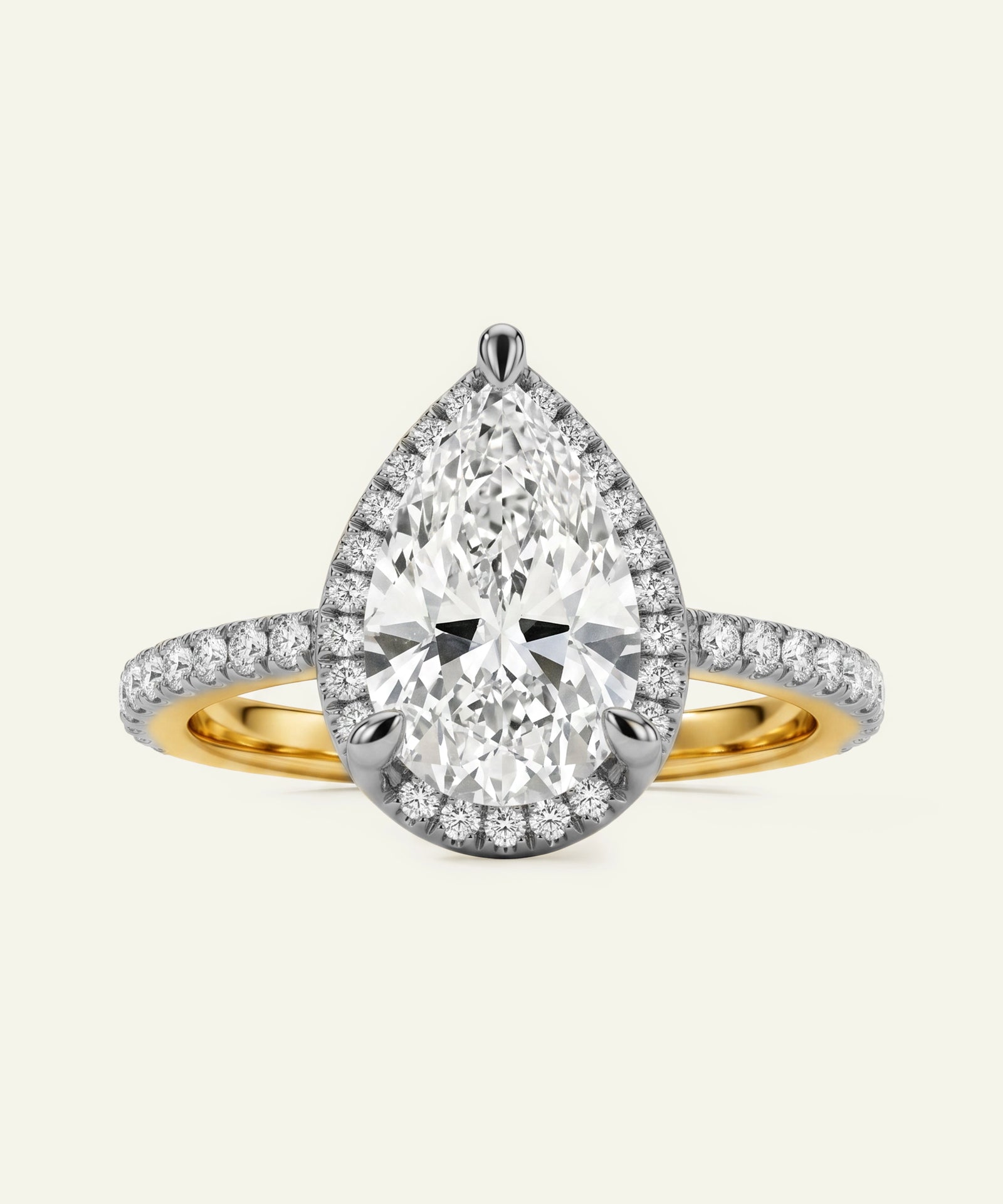 Diamond ring with pear-shaped center stone and gold band on a light gray background