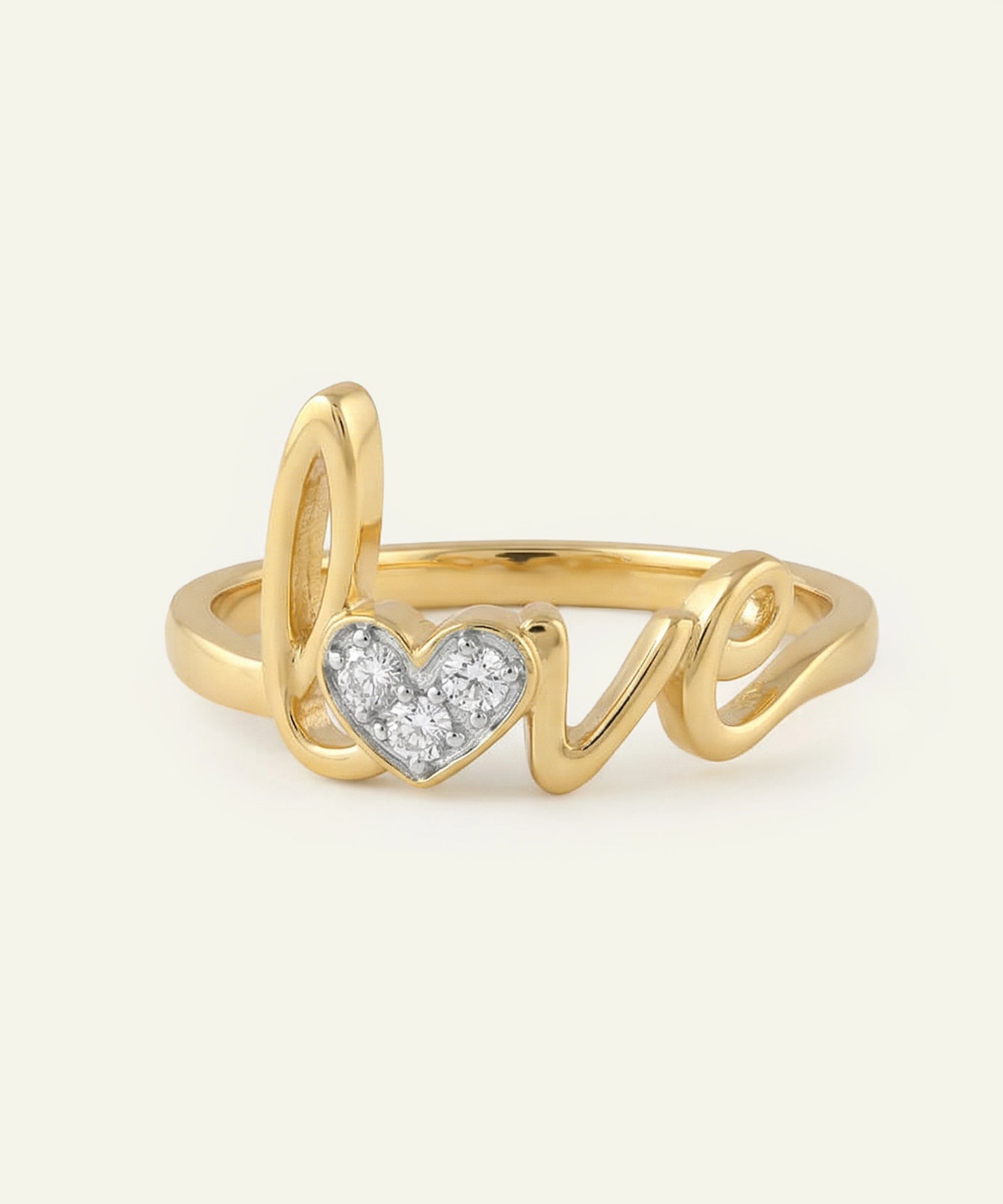 Gold ring with 'love' and heart design on a light beige background
