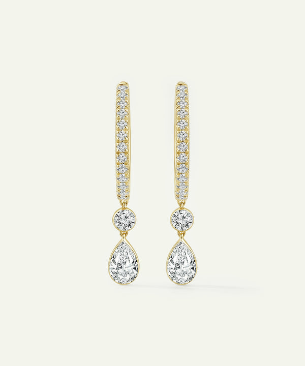 Gold teardrop earrings with clear gemstones on a light beige background