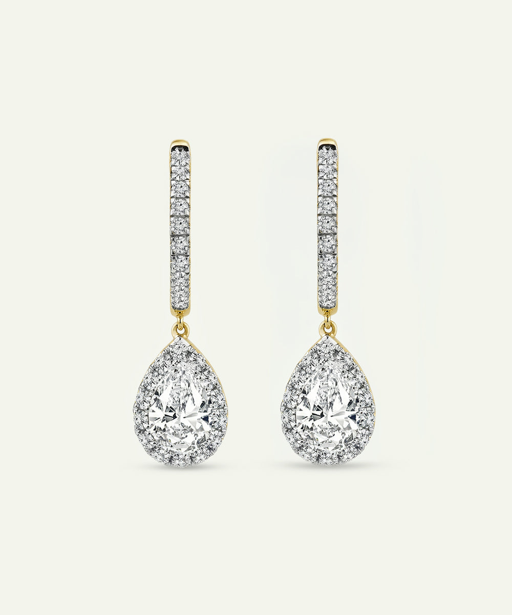 Pair of teardrop-shaped diamond earrings on a light beige background