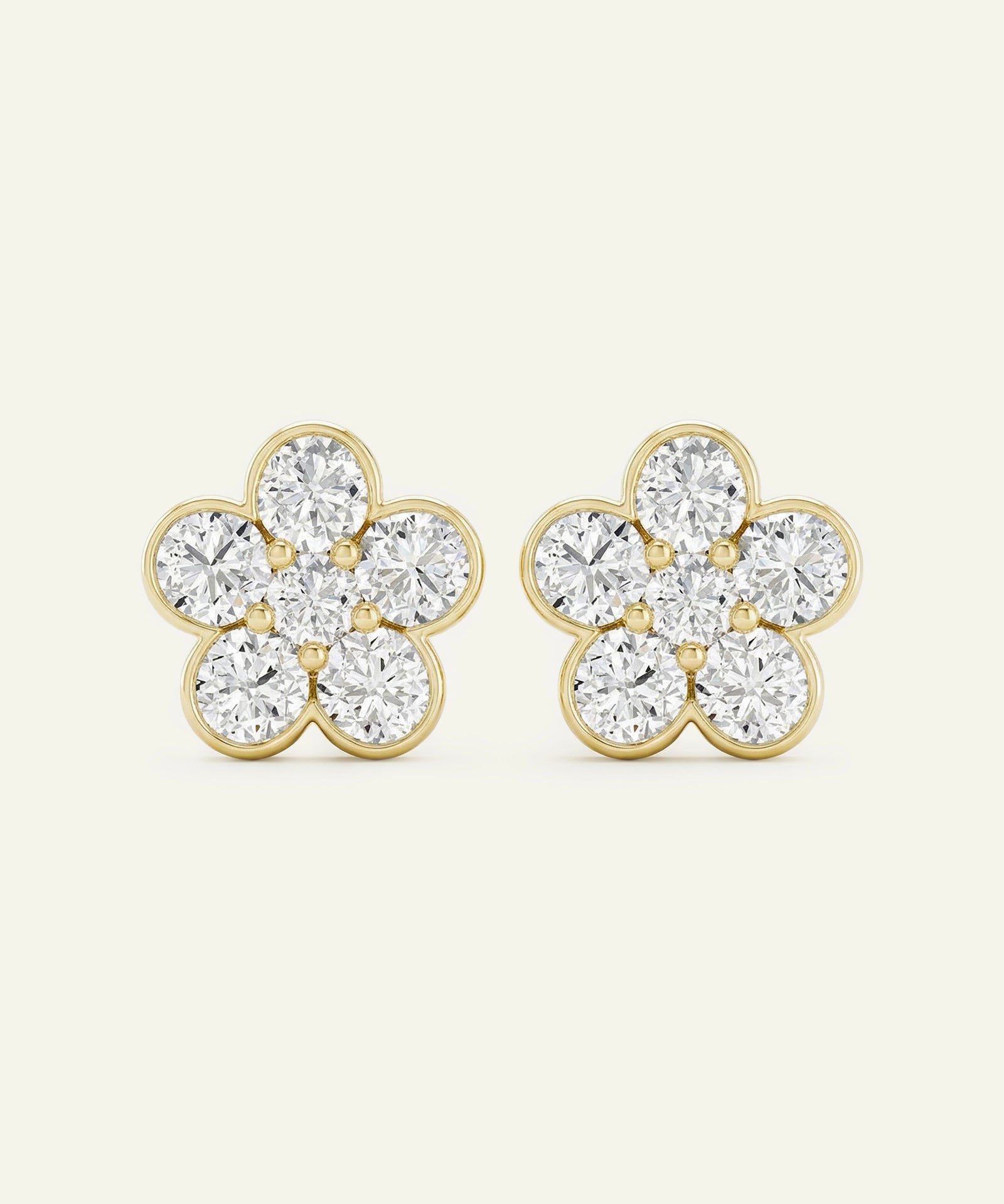 Pair of gold flower-shaped earrings with clear gemstones on a white background