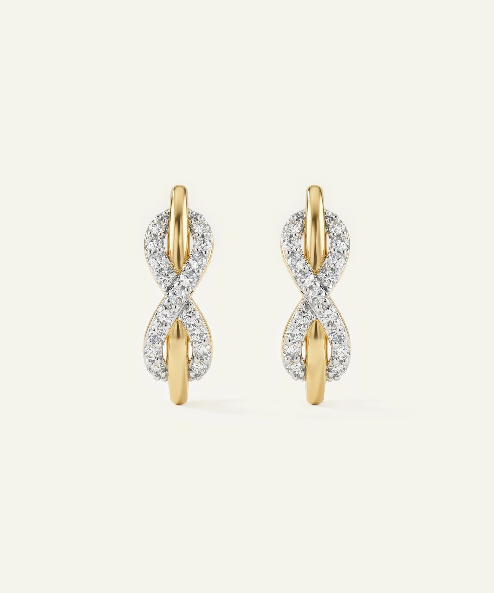 Gold and diamond earrings on a light beige background