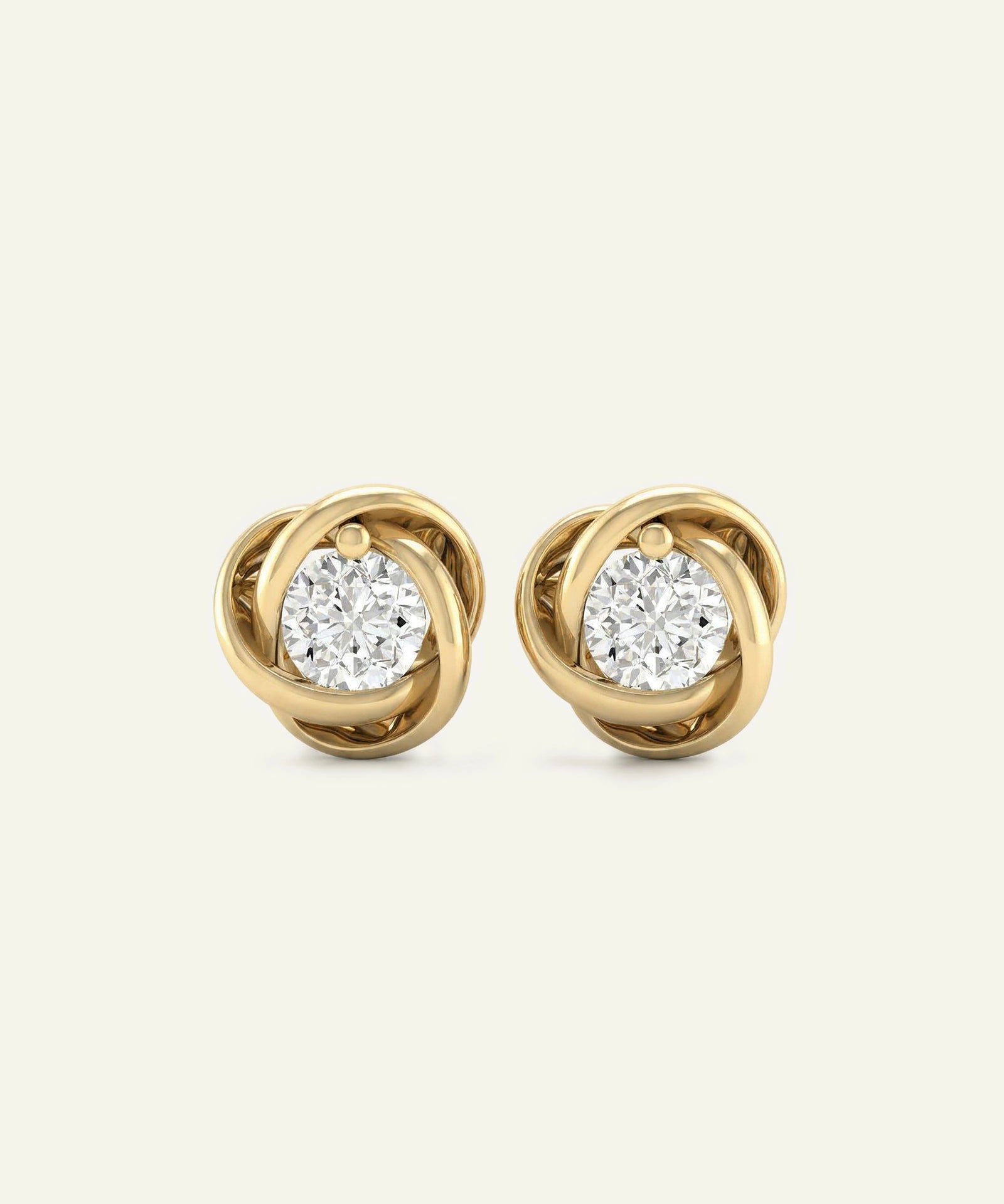 Gold earrings with diamond-like centers on a light beige background