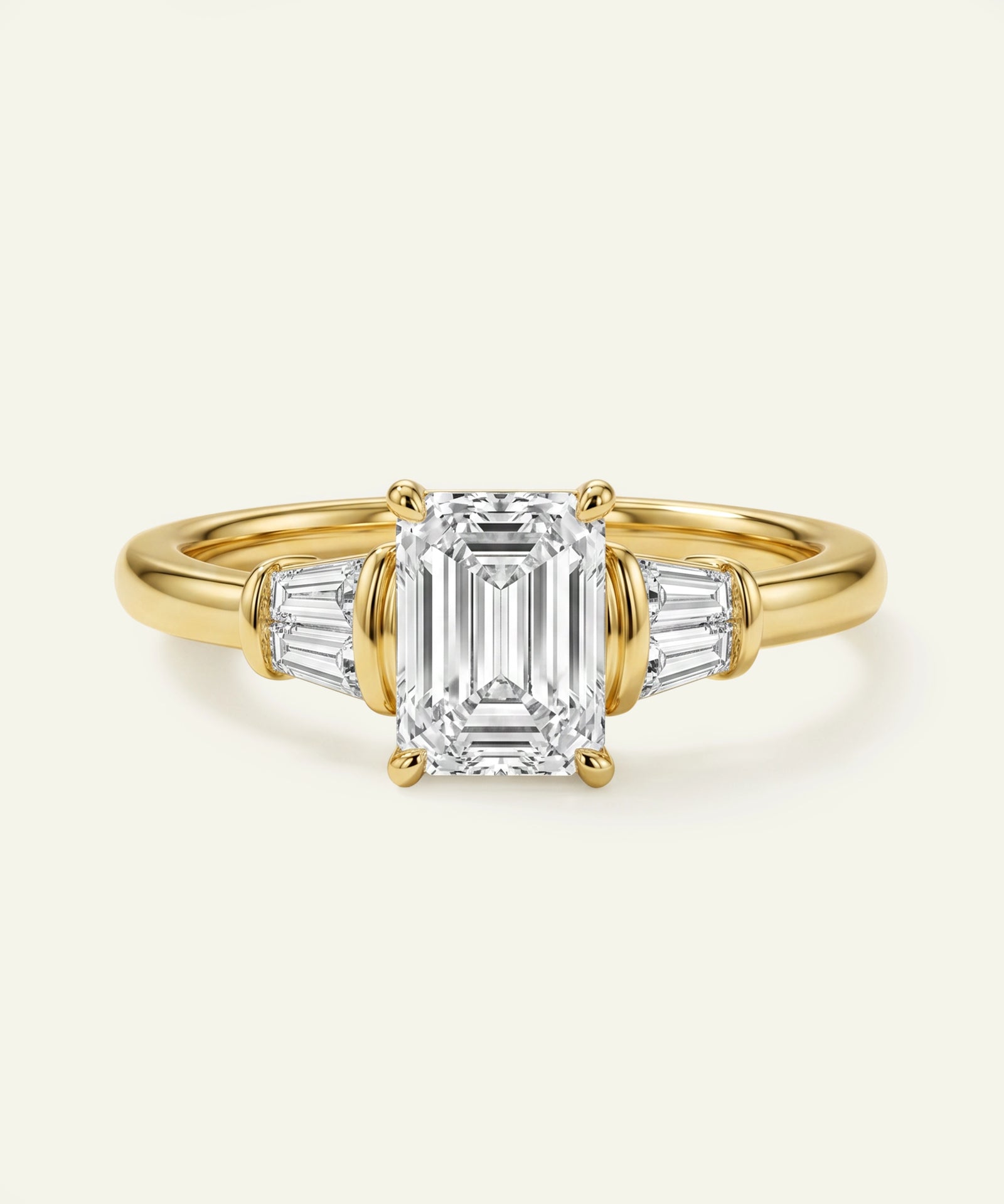 Gold ring with emerald-cut diamond and side stones on a white background