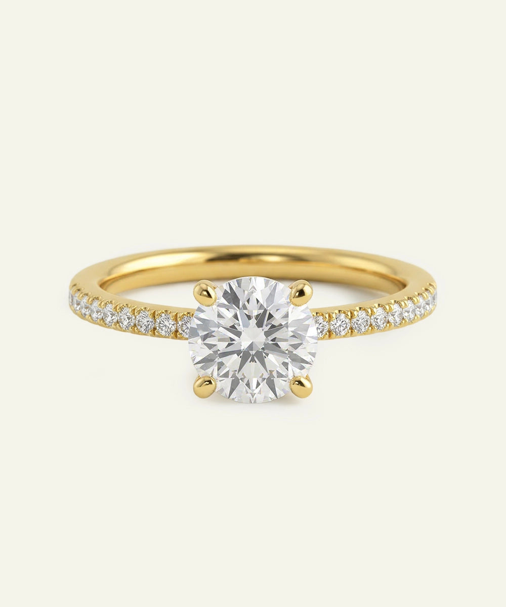 Gold ring with a large diamond and smaller diamonds on the band against a white background
