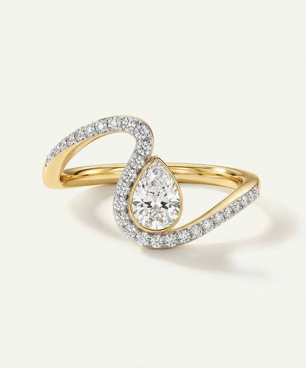 Gold ring with a pear-shaped diamond on a light gray background