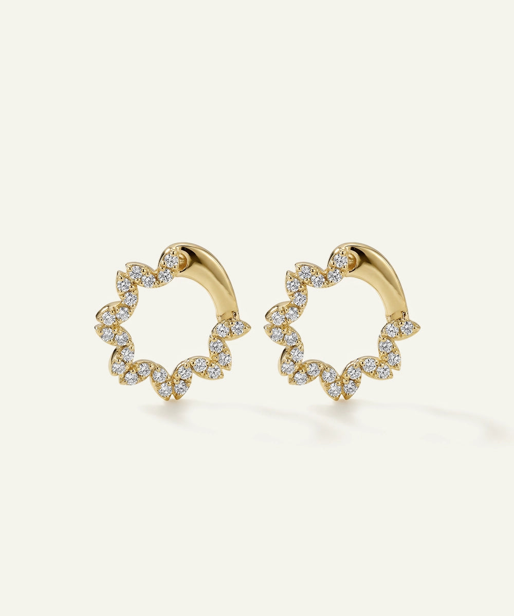 Gold hoop earrings with diamond accents on a light beige background