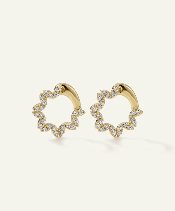 Gold hoop earrings with diamond accents on a light beige background