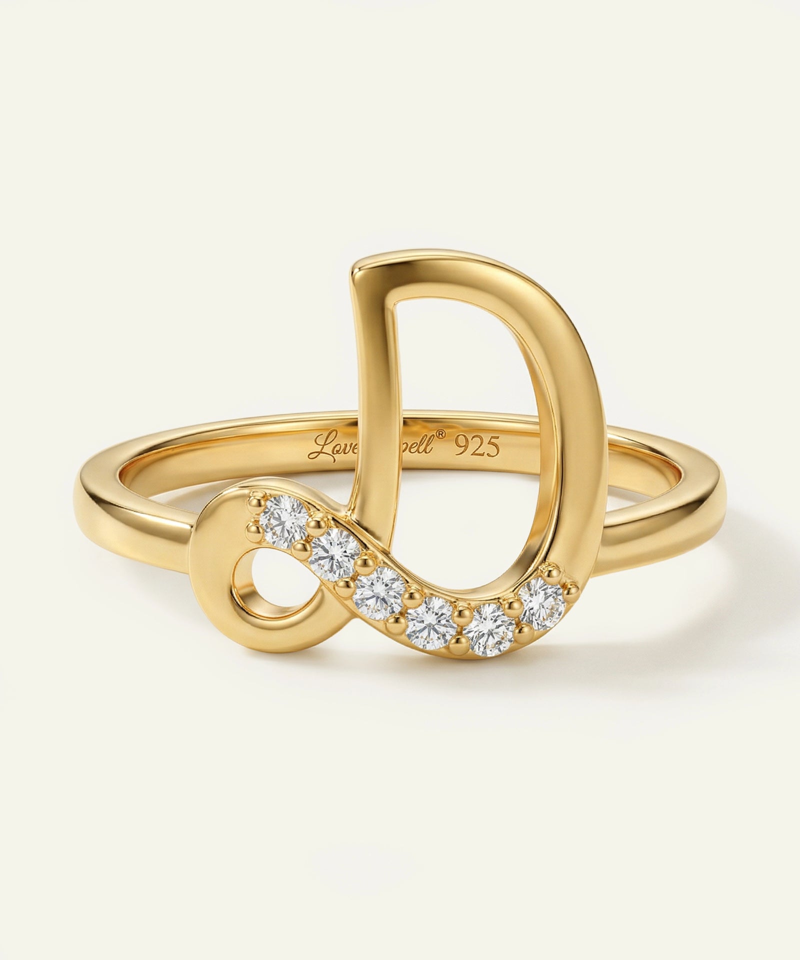 Gold ring with infinity symbol and diamonds on a light beige background