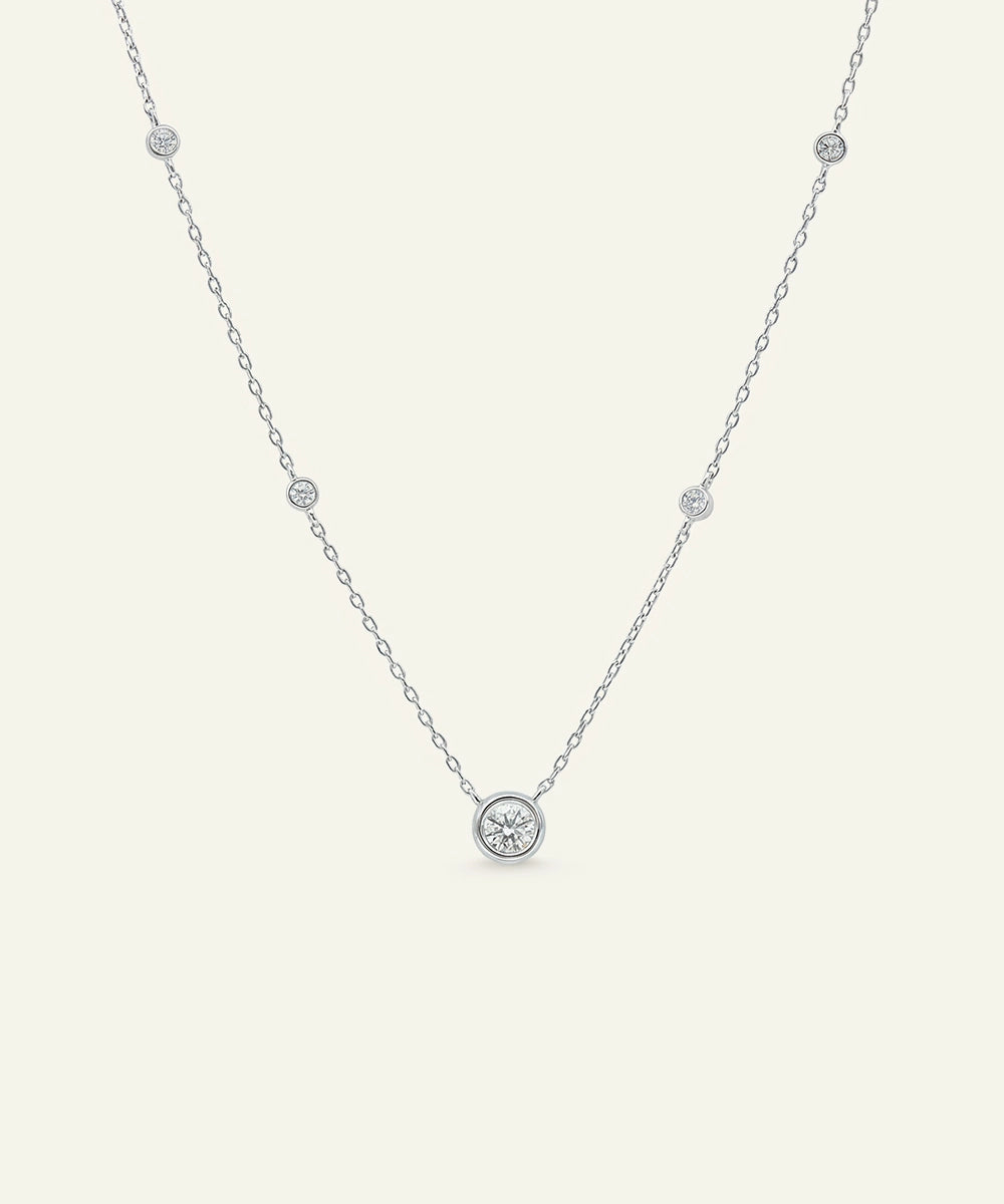 Delicate silver necklace with small round pendants on a light gray background