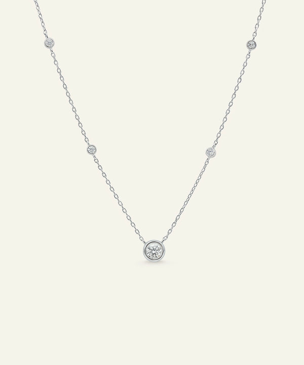 Delicate silver necklace with small round pendants on a light gray background