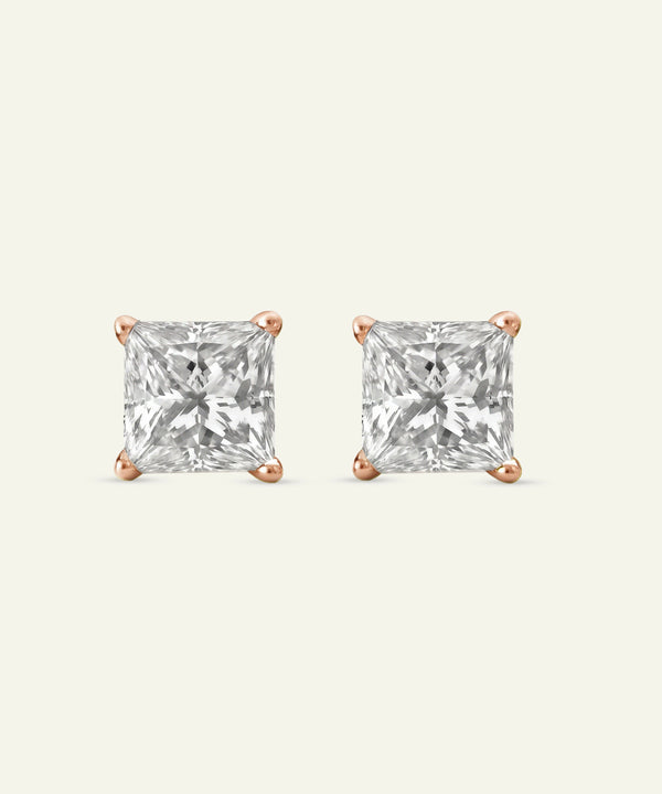 Pair of square-cut diamond stud earrings on a light gray background