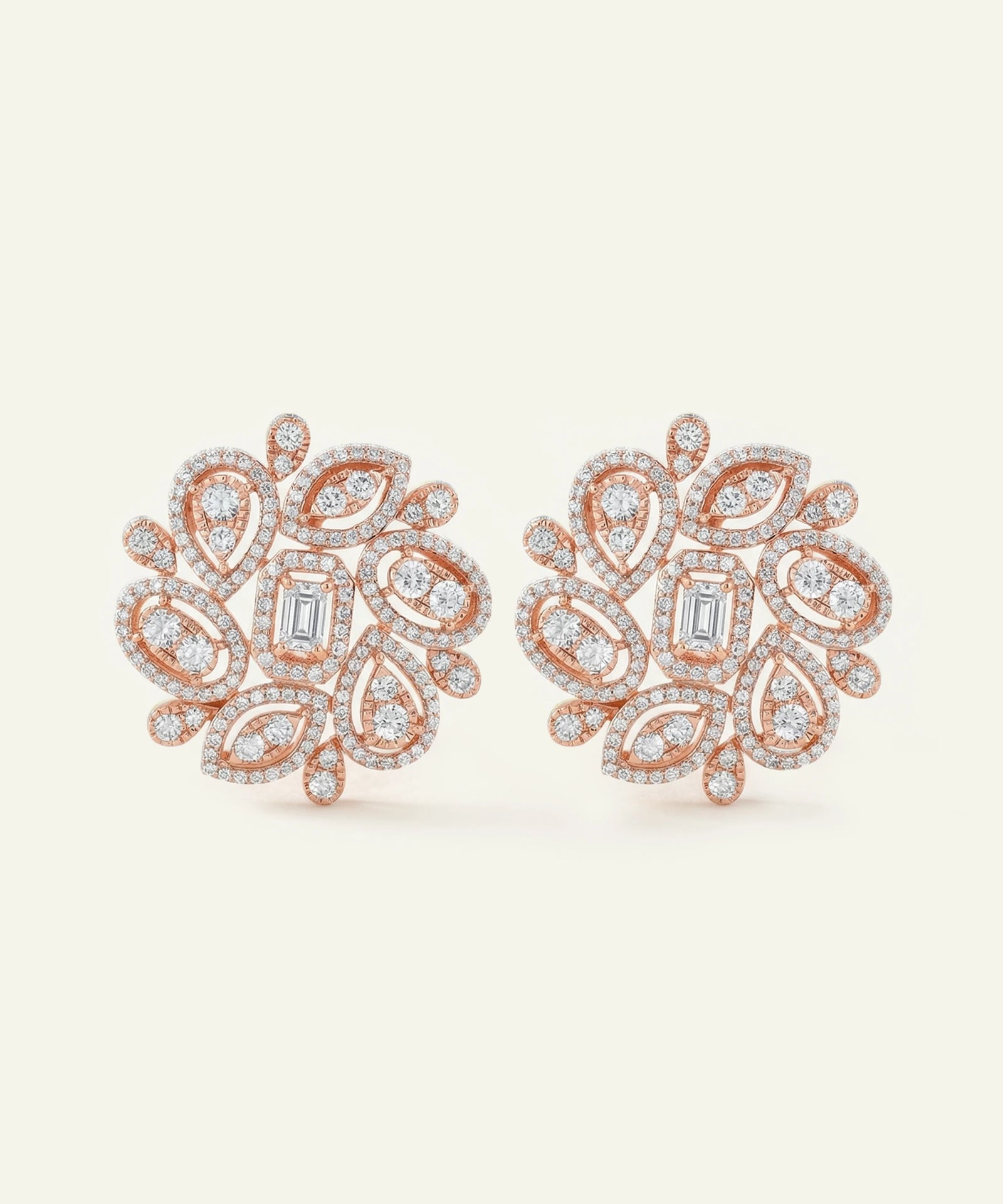 Rose gold earrings with diamond accents on a light beige background