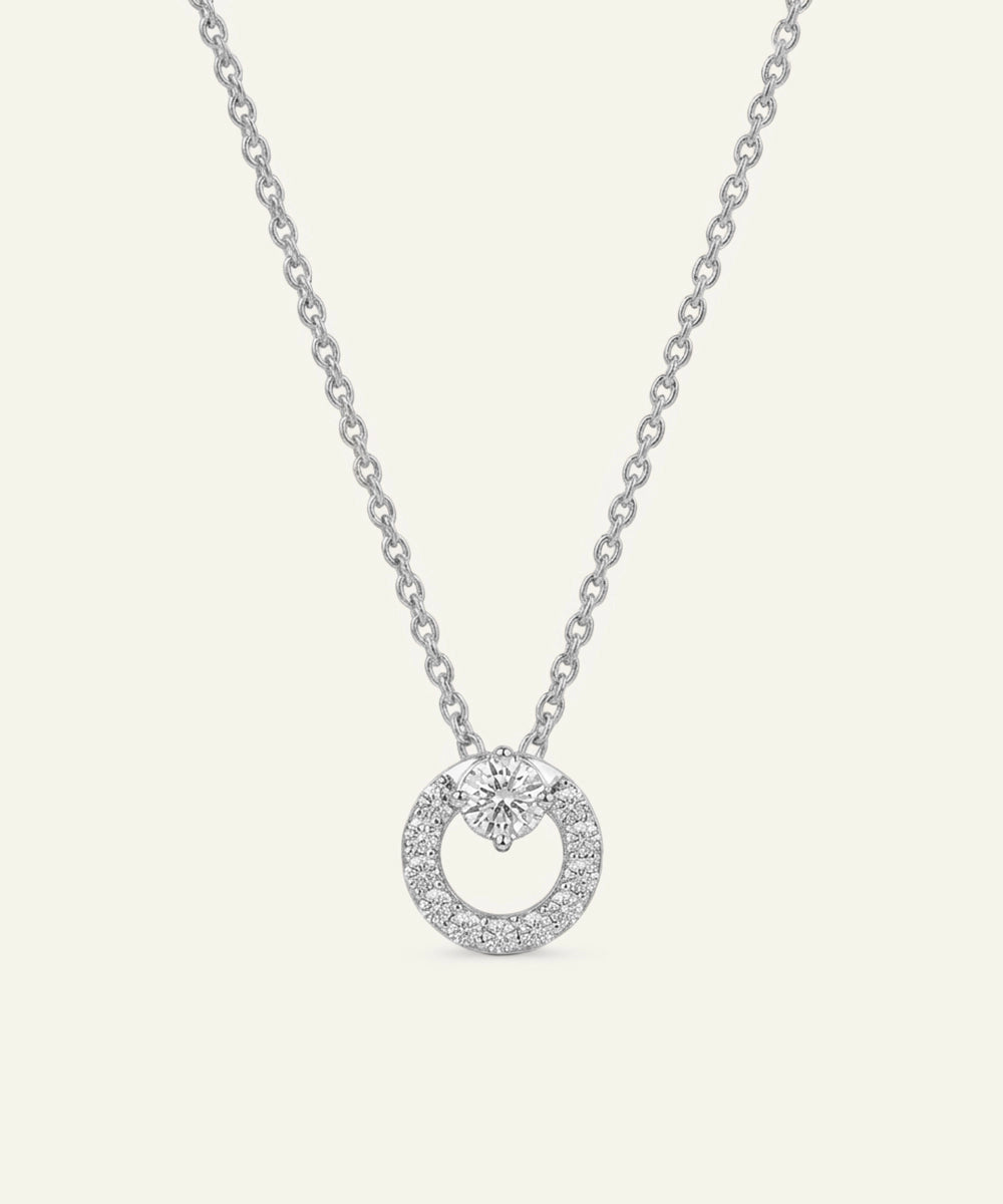 Silver necklace with a round pendant on a light gray background