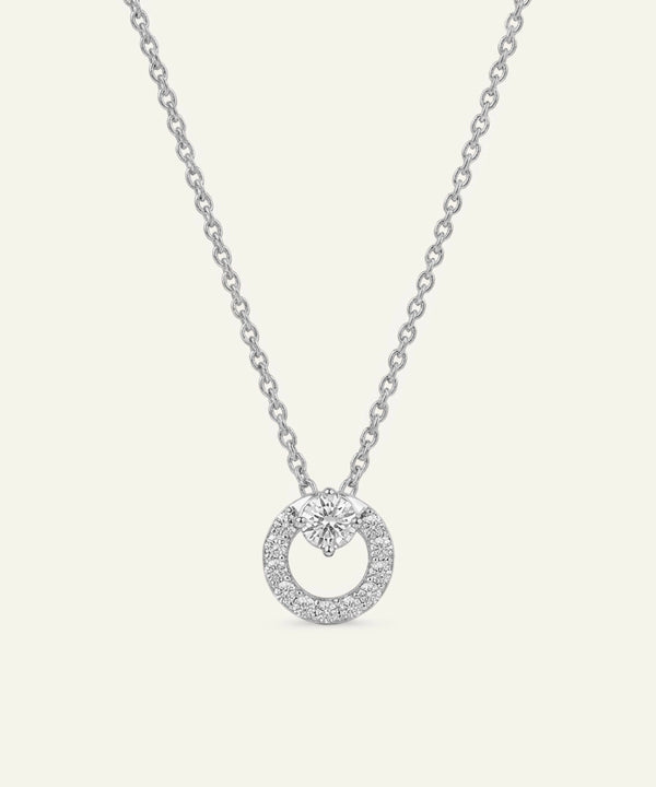 Silver necklace with a round pendant on a light gray background