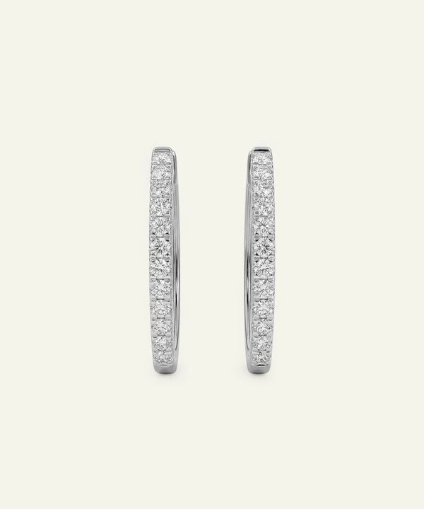 Pair of silver hoop earrings with embedded stones on a light gray background
